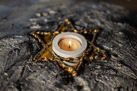 Burning wax candle in a golden star on a dark background.の写真素材