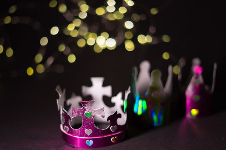 Three colorful, shiny paper crowns decorated with heart-shaped cutouts, symbolizing the Epiphany concept. Selective focus.の写真素材