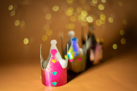 Three colorful, shiny paper crowns decorated with heart-shaped cutouts, symbolizing the Epiphany concept. Selective focus.の写真素材