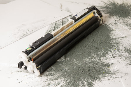 Printer toner cartridge placed on sheets of white paper and scattered with toner powder. Selective focus.の写真素材