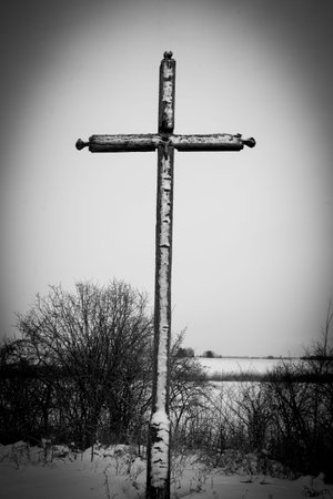 A weathered wooden cross standing alone in a snowy, barren winter landscape evokes themes of Good Friday, Golgotha, sacrifice, and Christian reflectionの写真素材