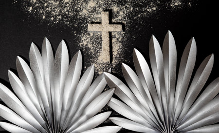 Silver palm leaves arranged around an ash cross on a black background emphasize the symbolism of Ash...