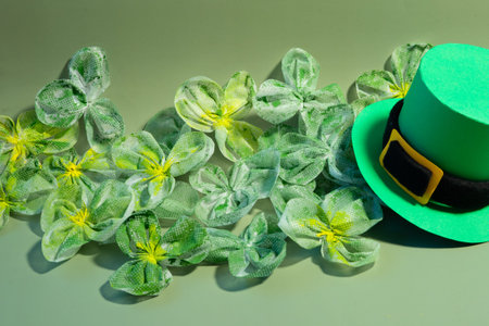 Green shamrockâlike fabric flowers with a bright green St. Patrickâs Day hat arranged on a green background in a top view layout with copy space.の写真素材