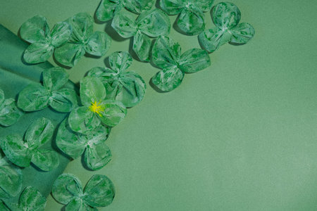 Handmade green shamrockâstyle fabric flowers arranged on a green background in a top view composition with copy space, symbolizing St. Patrickâs Day celebrationの写真素材