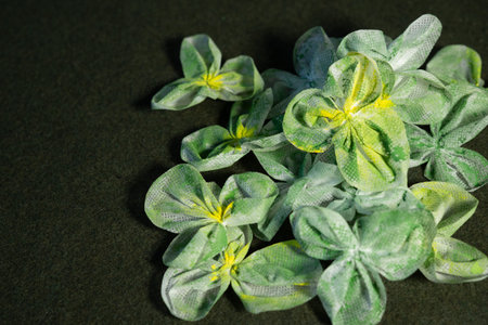 Handcrafted green shamrockâstyle fabric flowers are arranged on a dark green background in a top view composition with copy space for St. Patrickâs Day themes.の写真素材