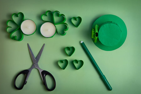St. Patrick's Day flat lay with green shamrocks, candles and green felt hat on green backgroundの写真素材