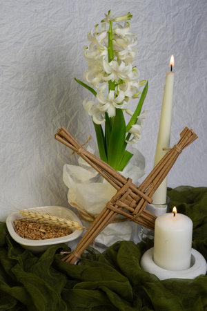 A Saint Brigidâ€™s Day altar with a woven Brigidâ€™s cross, white candles, grains, and a...