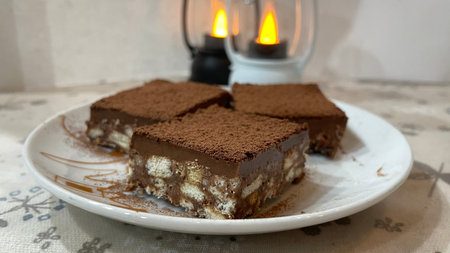 Tiramisu cake on a plate with a burning candle in the background