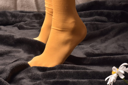 Women's feet in yellow socks on a black background with a flowerの写真素材