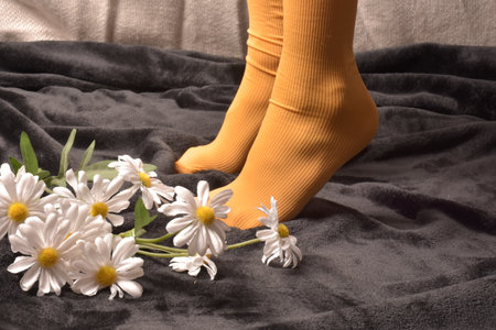 Female feet in yellow socks and white flowers on a black background.の写真素材