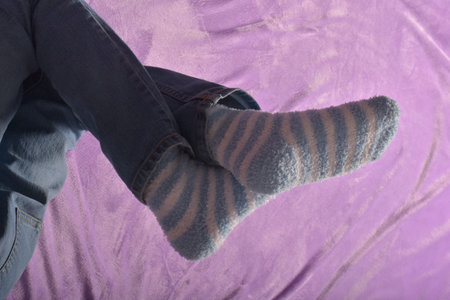 Legs in woolen socks on purple background, closeup of photo