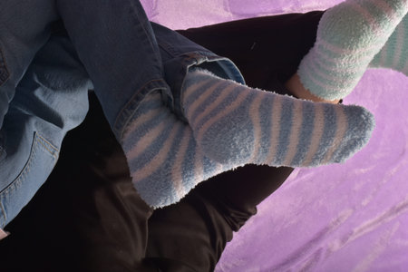 Legs of a young couple in woolen socks on a purple background