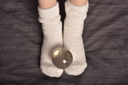 Womens feet in white socks with a glass ball on a black backgroundの写真素材