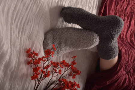 Woman in warm socks on bed, top view. Winter vacation conceptの写真素材