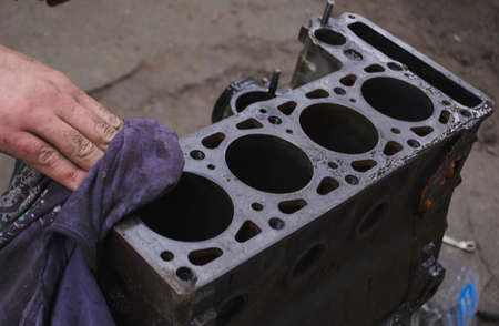 An auto mechanic is working on a car engine in a mechanics garage. repair service. authentic close-up shot.の写真素材