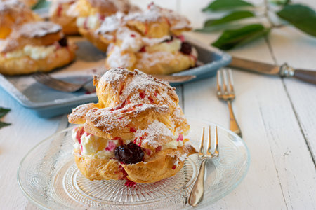 Fresh and homemade baked cream puff with whipped cream and sour cherry filling on a plate