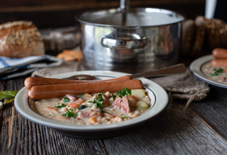 Rustic dinner table with a savory white bean soup, vienna sausages and bread.