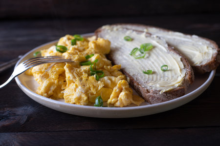 Scrambled eggs with butter bread. Plate with homemade fresh fried eggs and delicious German...