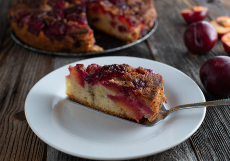Piece of fruit cake on a plate. Fresh and homemade baked plum cake upside down. Served on a plate...