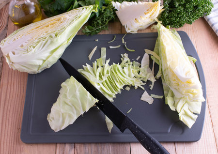 Preparation of fresh and raw cabbage. Chopping and cutting. Served on a cutting board with a kitchen...