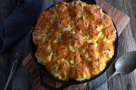 Traditional Irish savory shepherds pie with potato cheddar cheese topping. Served in a rustic cast iron pan on a dark wooden table background. Closeup and overhead viewの写真素材