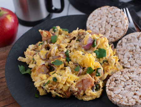 Workout meal with scrambled eggs, ham, onions, herbs and brown rice crackers