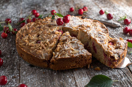 Rustic cherry cake or cherry with almond topping. Fresh and homemade baked. Served isolated on wooden table background with copy spaceの写真素材