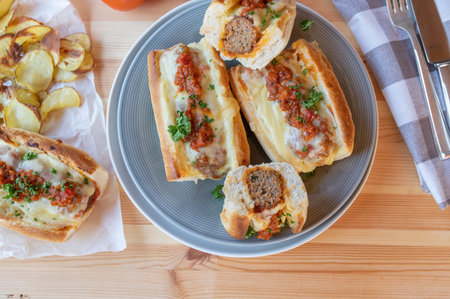 Meatball sandwiches or subs with cheese and homemade potato chips on a dinner table. flat layの写真素材