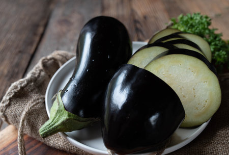 Raw and uncooked eggplant isolated on wooden table background with cross section viewの写真素材