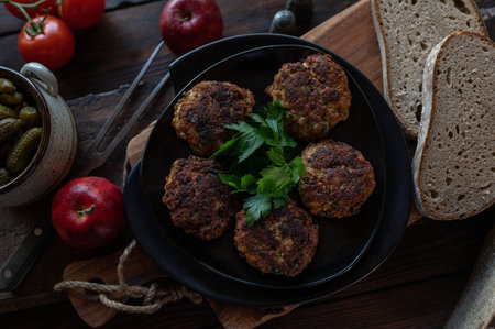 Rustic bread meal with warm pork meatballs, pickles and rye bread on moody wooden table background from aboveの写真素材
