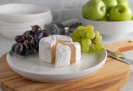 Brie or soft cheese, with dark and green grapes on a plateの写真素材
