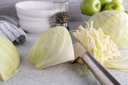 Chopped white cabbage on a cutting board on kitchen counter with chopper knife.の写真素材