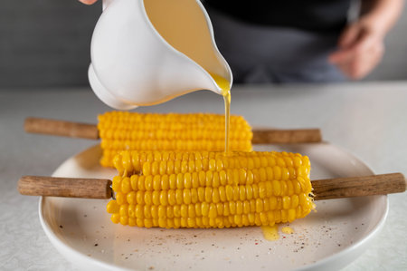 Pouring melted butter over corn on the cobの写真素材