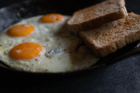 Fried eggs with toast in a cast iron panの写真素材