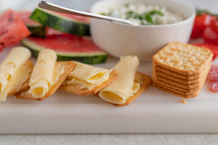 Appetizer with cheese and crackers on a white cutting board