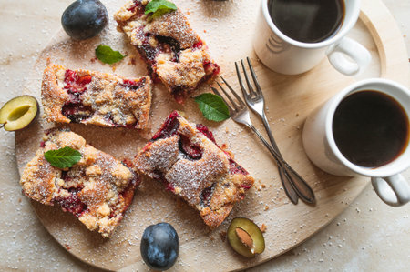 Slab pie with plums and crumbles on a wooden platter with coffeeの写真素材