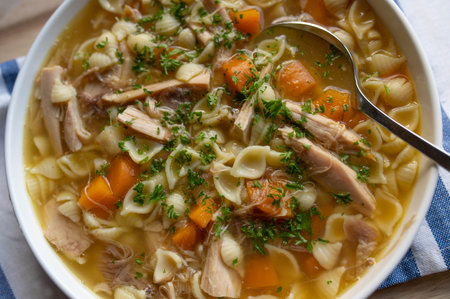 Chicken soup with noodles, carrots and parsley in a bowl.