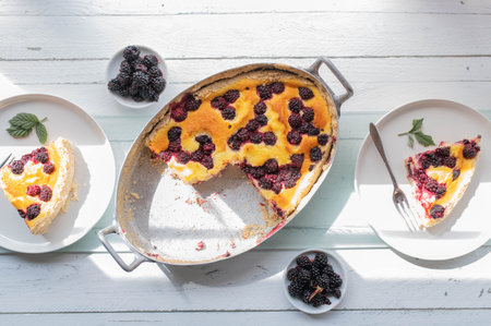 Delicious german cake with blackberries and sour cream pudding topping. Served ready to eat on white wooden table background from above.の写真素材