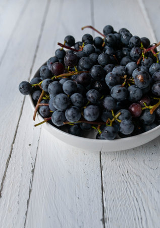 A bowl with freshly picked black grapes isolated on white background with copy space
