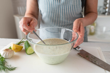 Close-up of woman's hands making Turkish cacik. Delicious yogurt sauceの写真素材