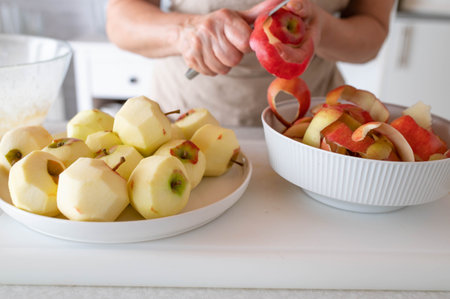 Close up of woman peeling apple in the kitchen. Healthy eating and vegetarian conceptの写真素材