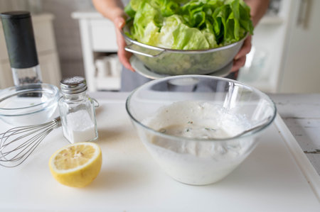Close up of woman mixing ingredients for salad in the kitchen at homeの写真素材