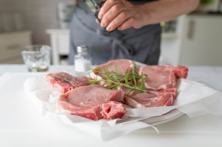 Chef preparing fresh pork chops with rosemary on a cutting boardの写真素材