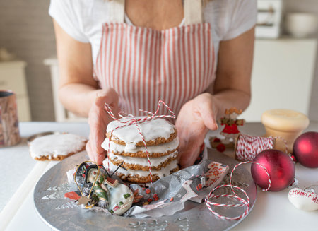 Woman decorating Christmas gingerbread cookies with white icingの写真素材