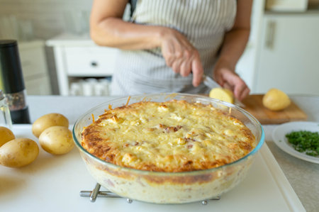 Close up of woman cooking homemade potato casserole in the kitchenの写真素材