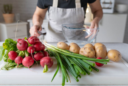 Woman with apron in the kitchen with healthy food. Raw vegetables on a cutting board.の写真素材