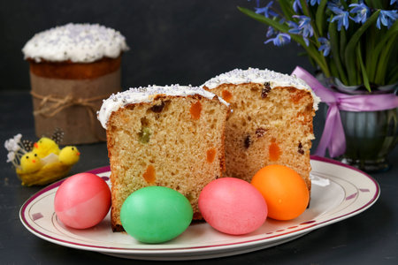 Easter cakes and colorful eggs are located on a plate on a dark background