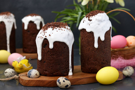 Still life with homemade chocolate Easter cakes and colorful eggs on a dark background