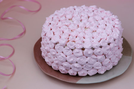 Festive cake covered with pink cream on a pink background