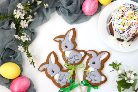 Easter gingerbread in the form of cute rabbits on sticks located on a white background, top view,...